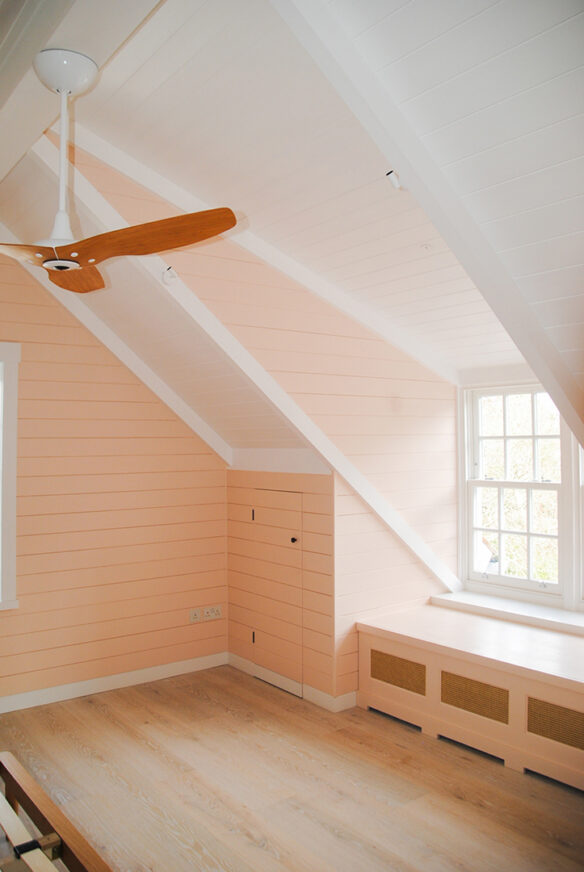 interior bedroom and peach colour walls with double aspect windows and a ceiling fan