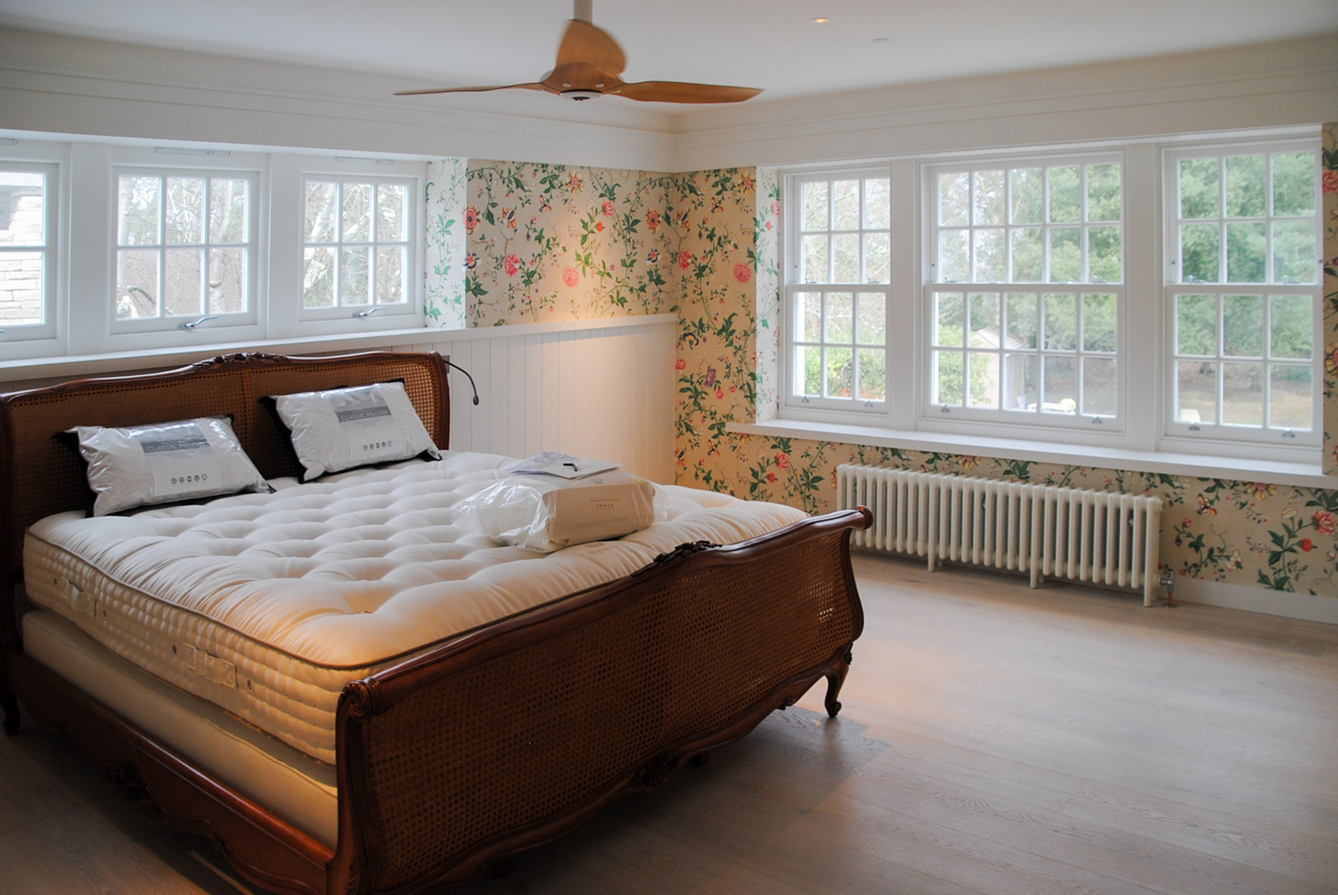 master bedroom with double aspect windows and floral wallpaper