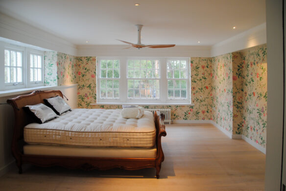 master bedroom with double aspect windows and floral wallpaper