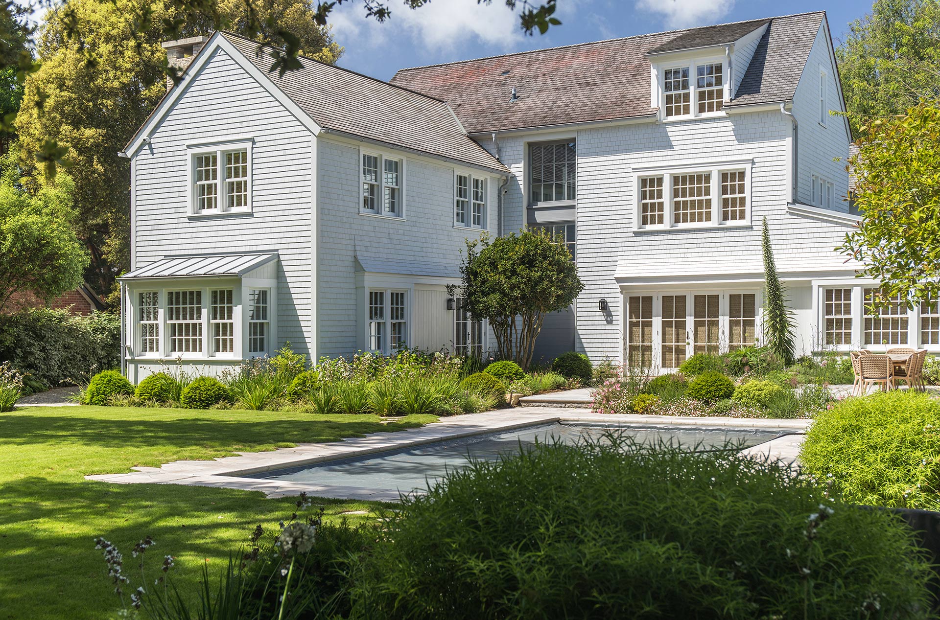 rear view of new England style house with patio garden and outdoor swimming pool