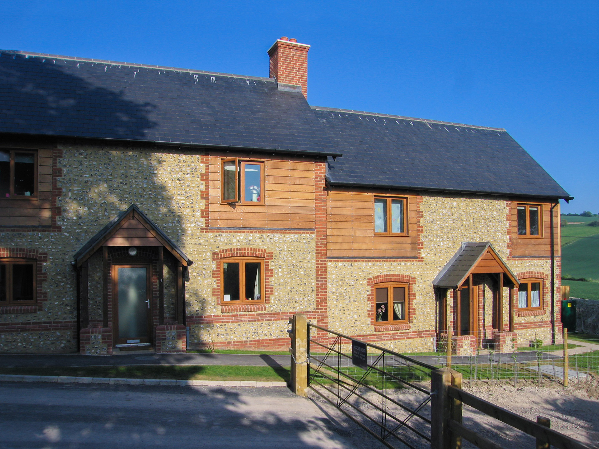 front view of two houses with stone walls and timber cladding