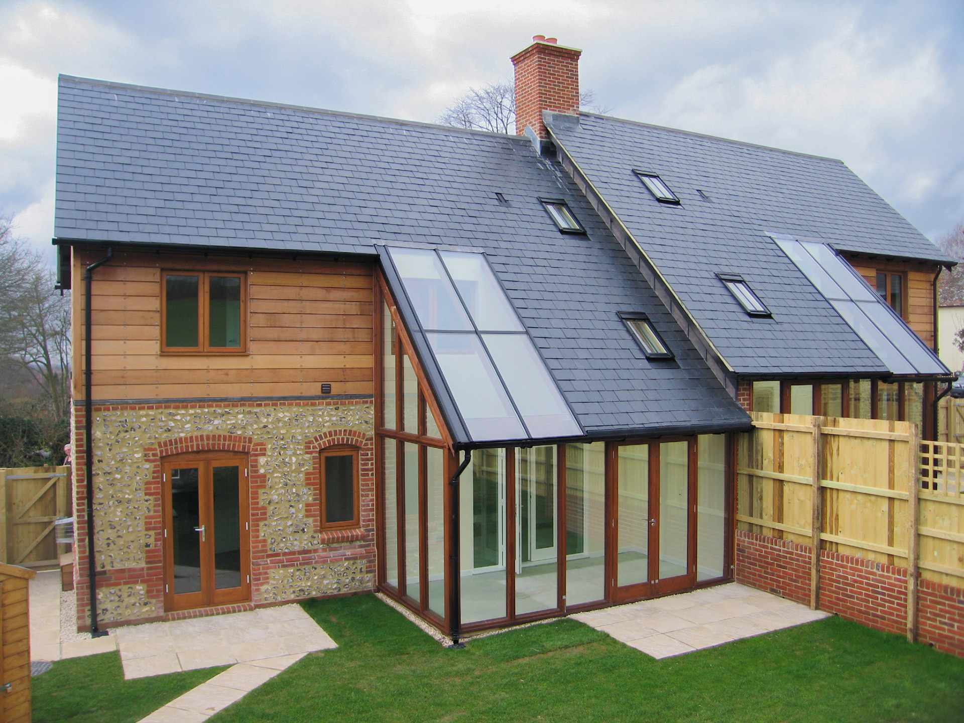 semi detached house with timber cladding and a cat slide roof