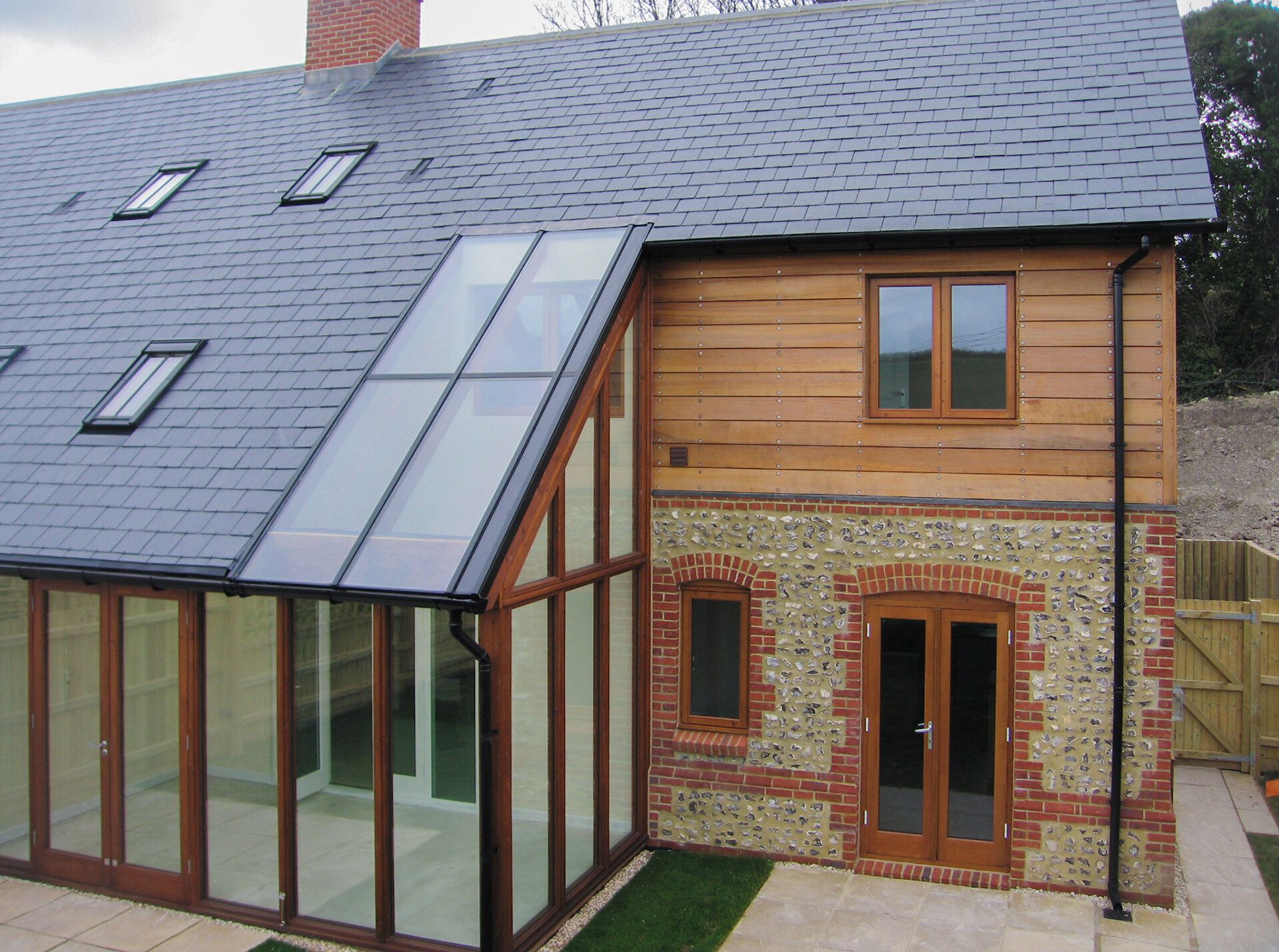 semi detached house with timber cladding and a cat slide roof