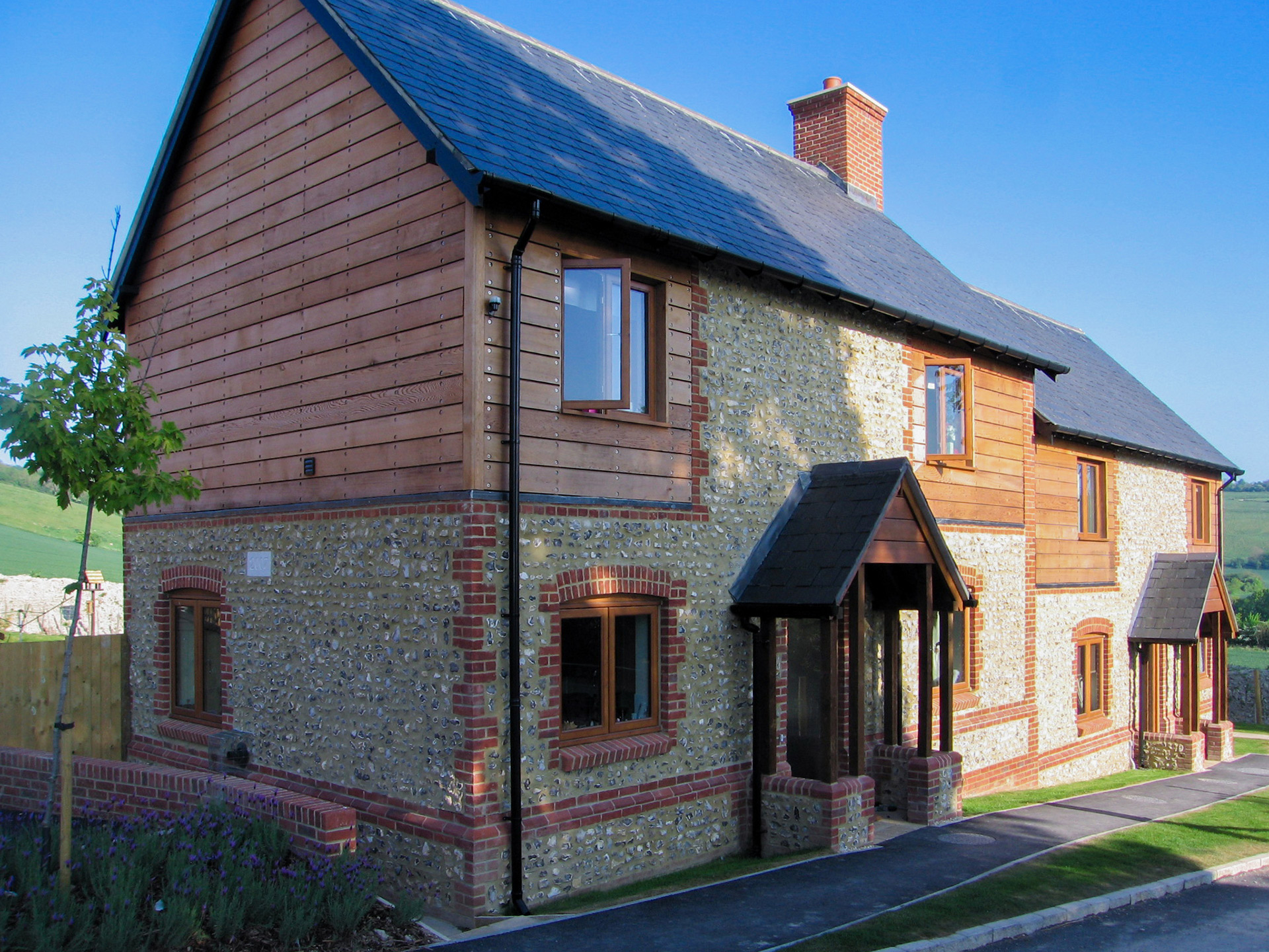 front view of two houses with stone walls and timber cladding