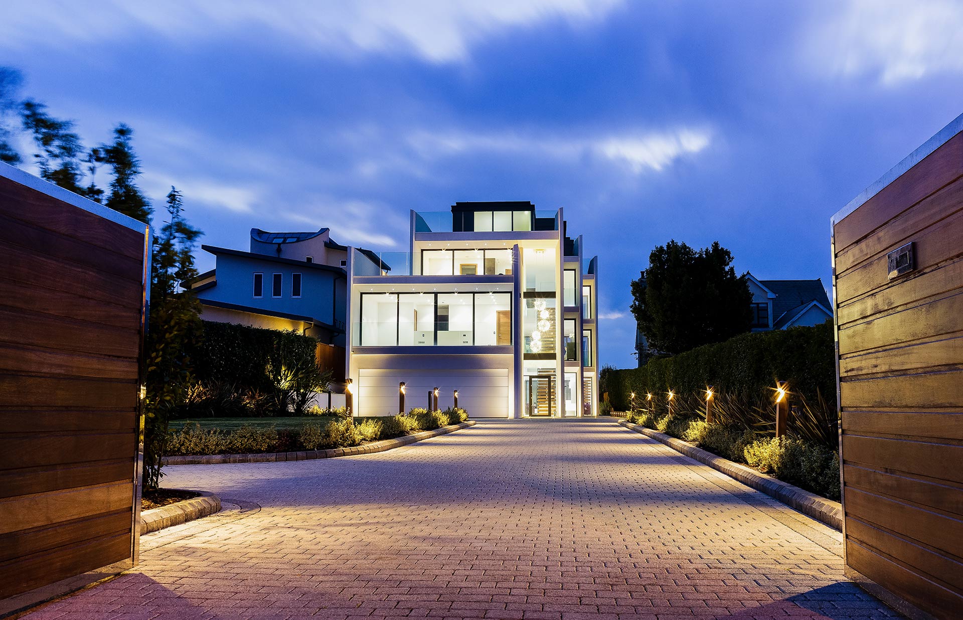 view of modern house from driveway at night lit up