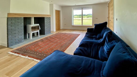 minimalistic interior living area with white log burner and large blue sofa