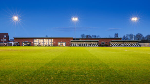 wimborne town football clubhouse with pitch in front at night with lights on