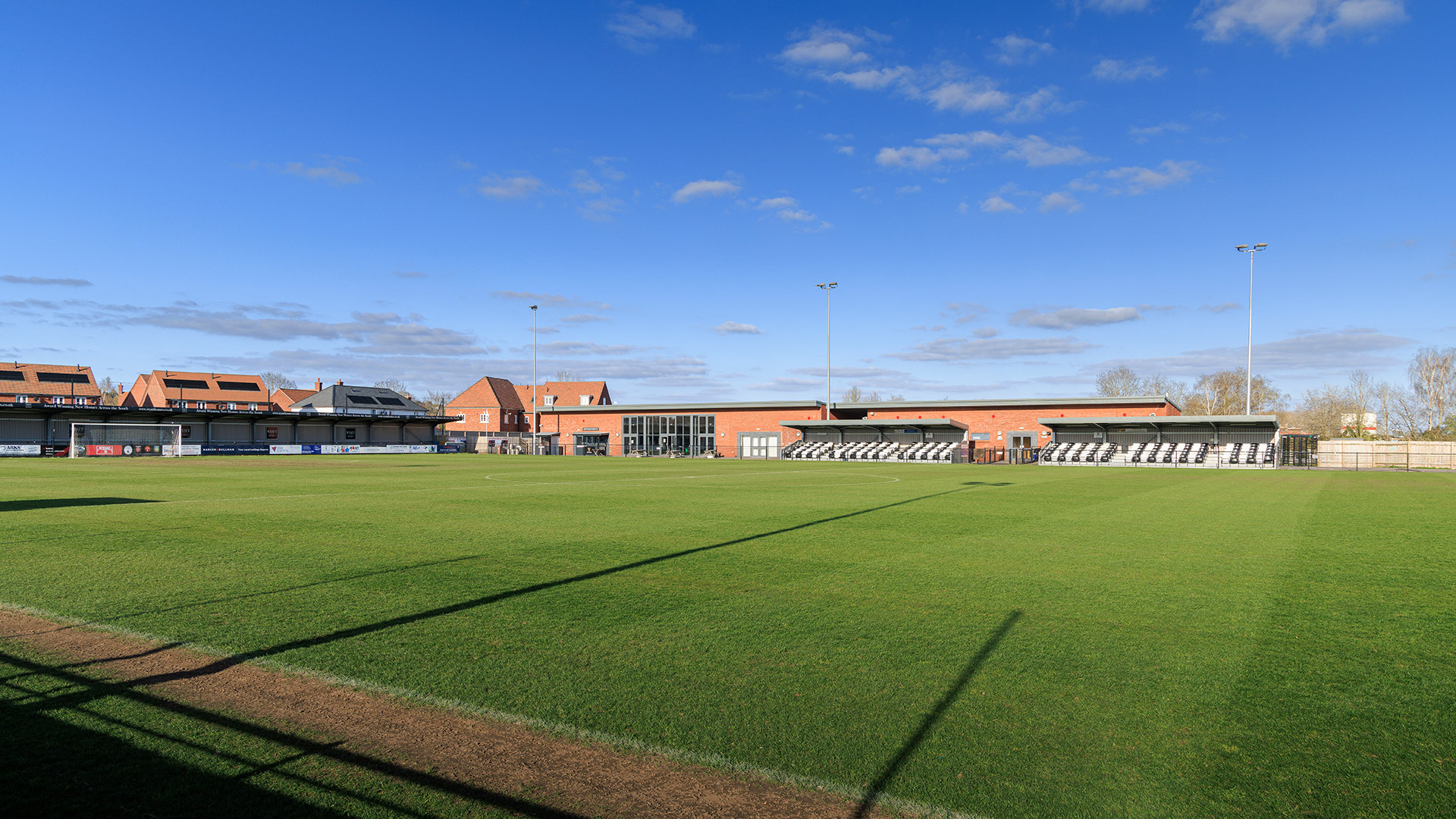 football pitch with clubhouse and supporters stands in background