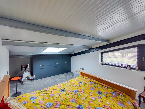 modern bedroom with exposed metal beams and slanting roof