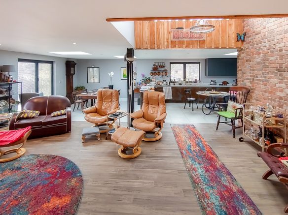 open plan living and kitchen space with double height area and exposed brick wall