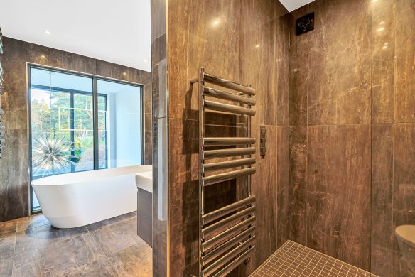 modern brown marble toned bathroom with freestanding bath and internal window