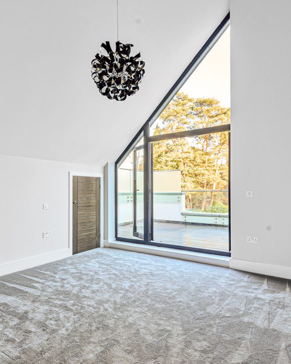 empty bedroom with sloping ceiling and glass window wall leading to patio