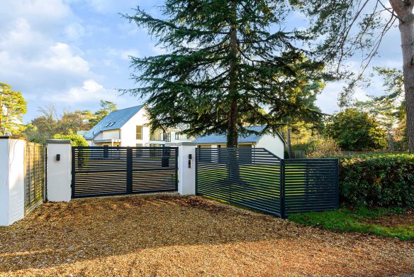 closed black electric entrance gate with contemporary house behind