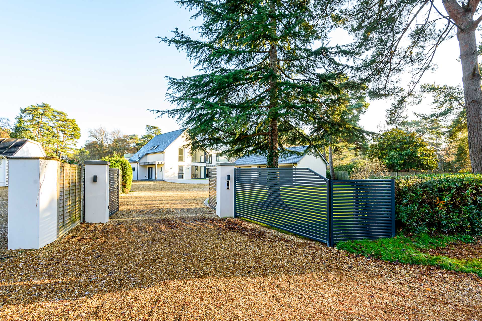 open black electric entrance gate with contemporary house behind