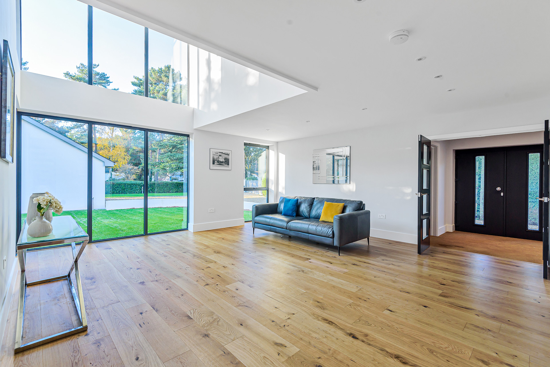 open plan living and entrance space with double height areas and large windows looking to garden