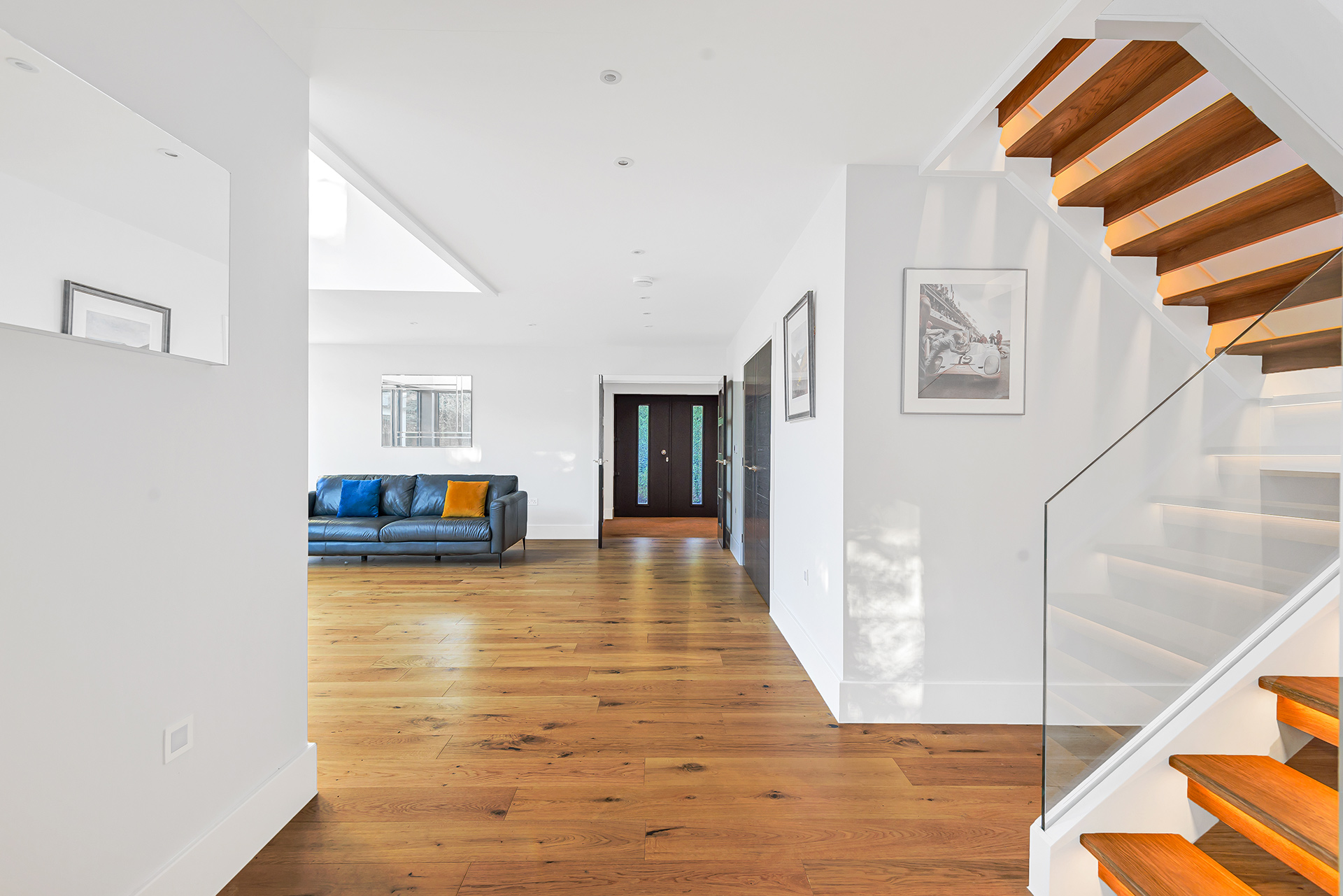 open plan living area with lit up wooden dog legged staircase