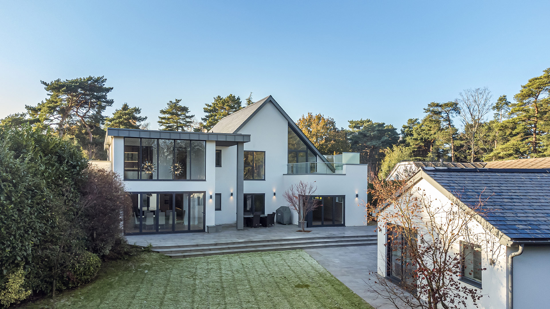 rear view of contemporary white house with zinc cladding and outhouse