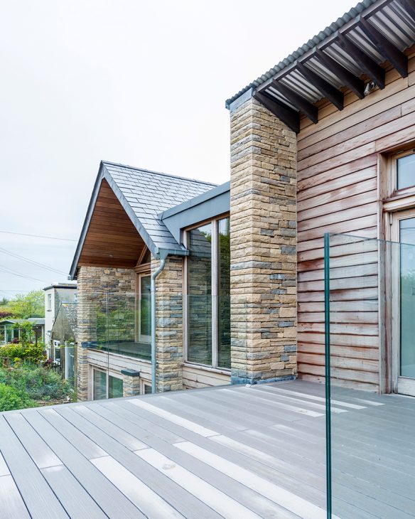 rear view of house from balcony with glass balustrade and timber cladding walls