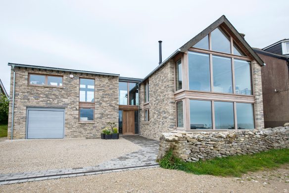 front view of house with stone walls and parking area