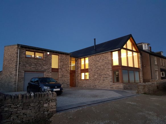entrance approach of house with stone walls at night with lights on