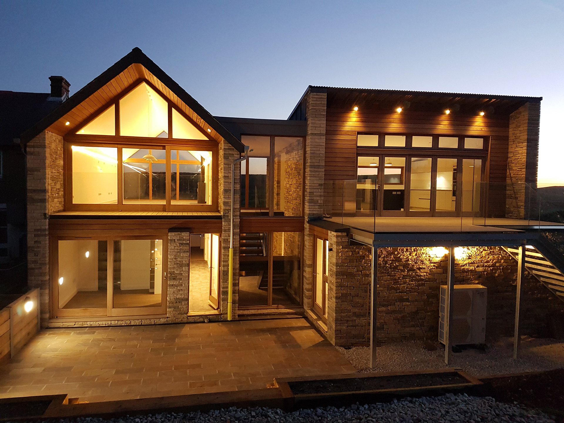 rear view of house with stone walls at night and lights on