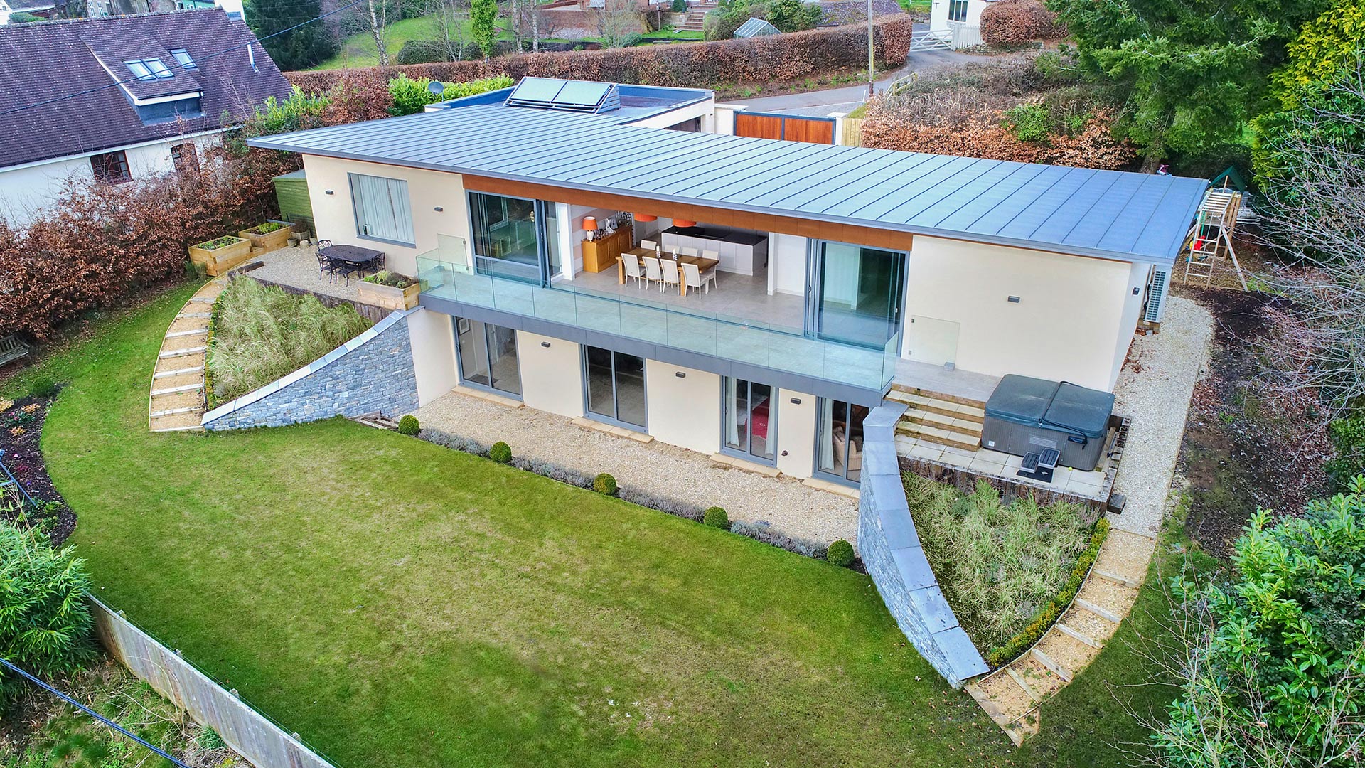 aerial view of modern house with leveled garden and large sliding doors to balcony on first floor