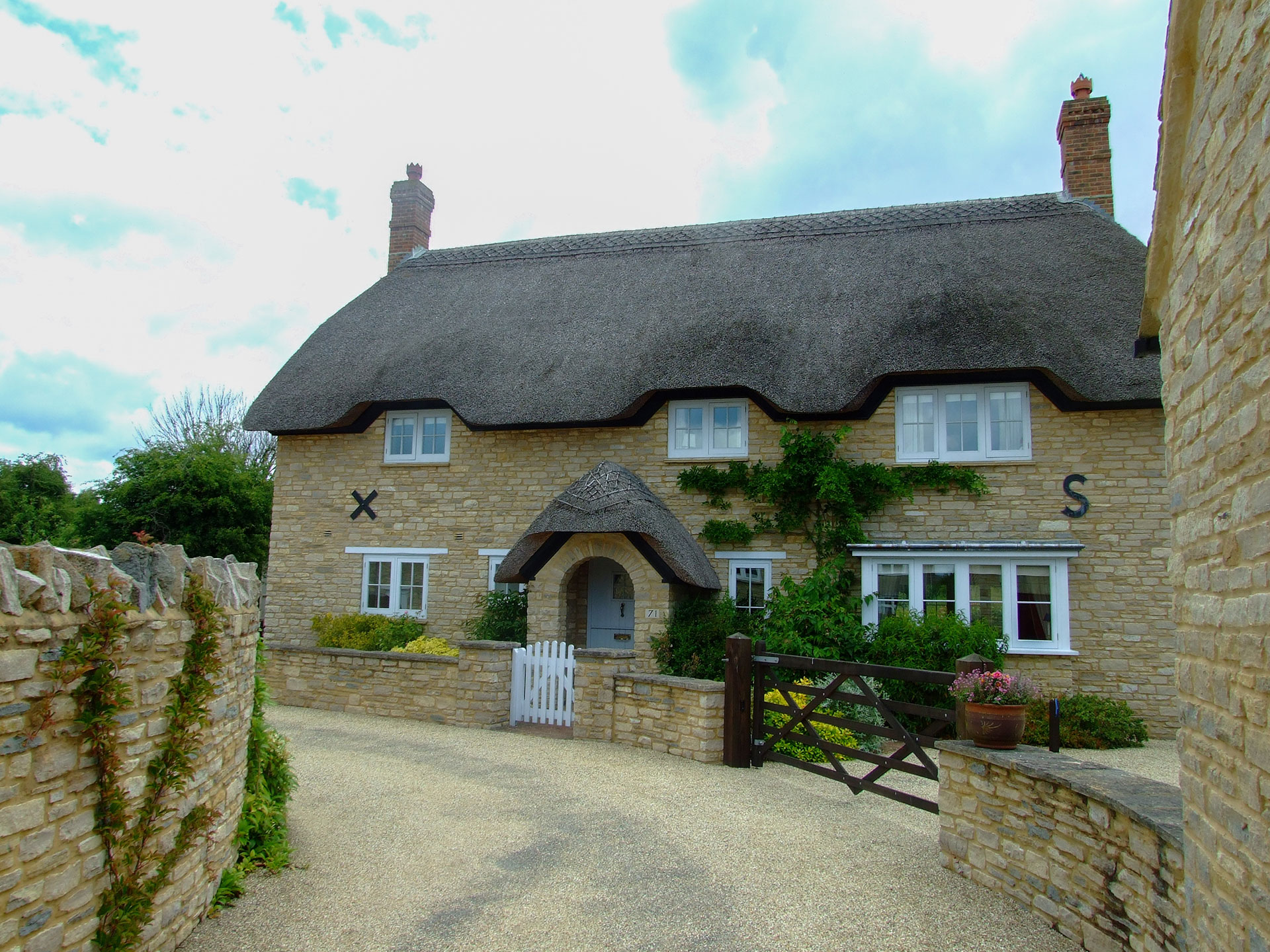 new thatched cottage with stone walls and idyllic driveway