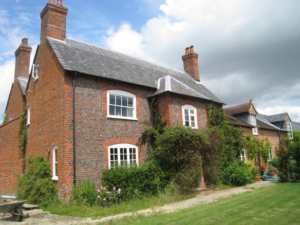 front view of house with red bricks and foliage around entrance