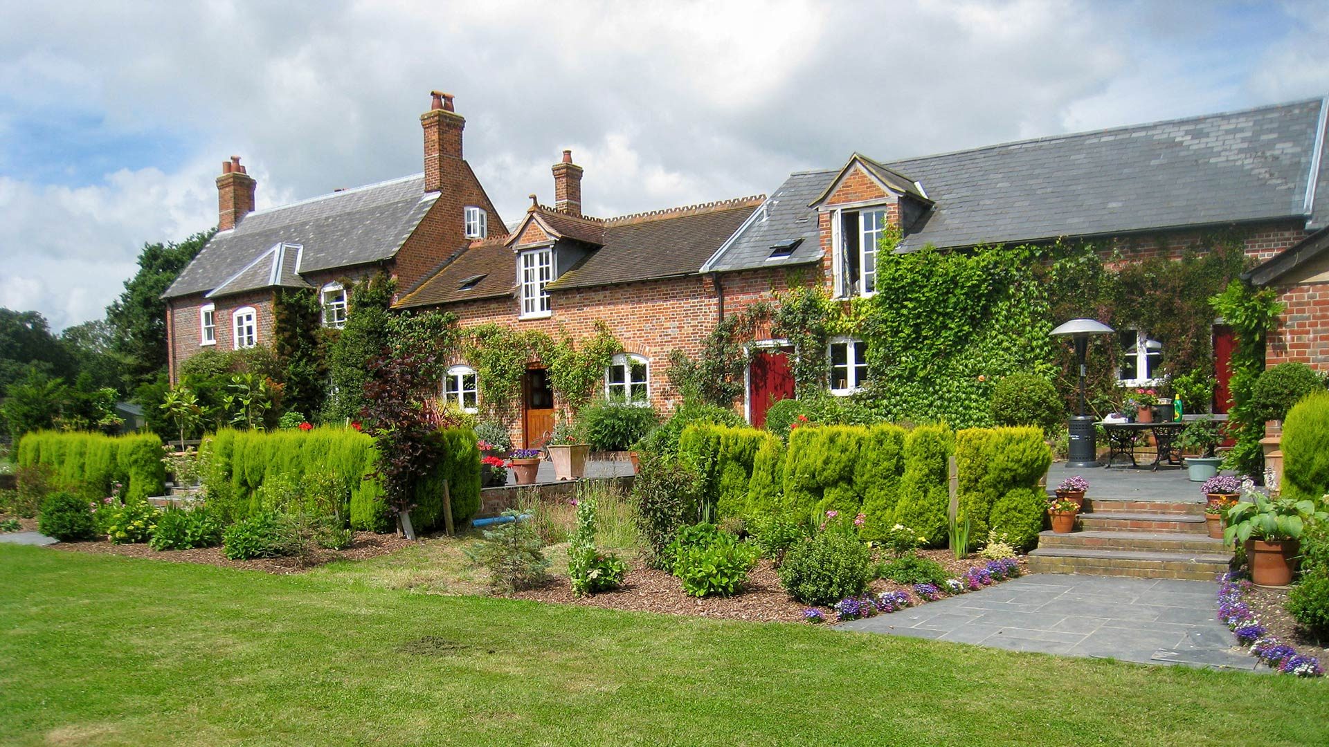 large converted farmhouse with various roof heights taken from garden