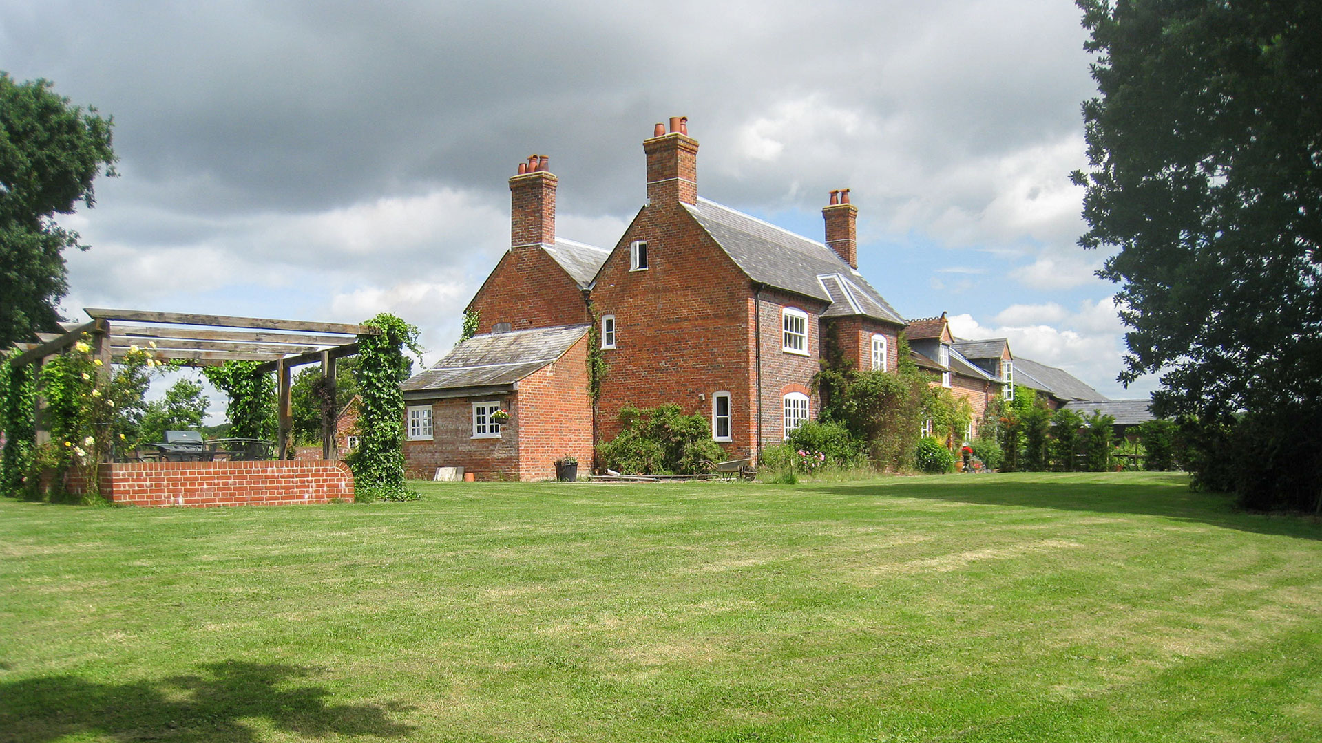large traditional red brick house with grass lawn garden