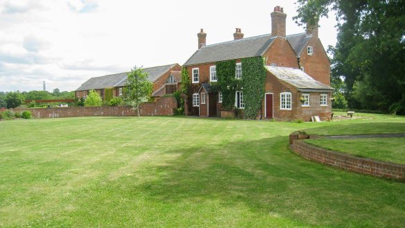 front view of large traditional red brick house with grass lawn garden