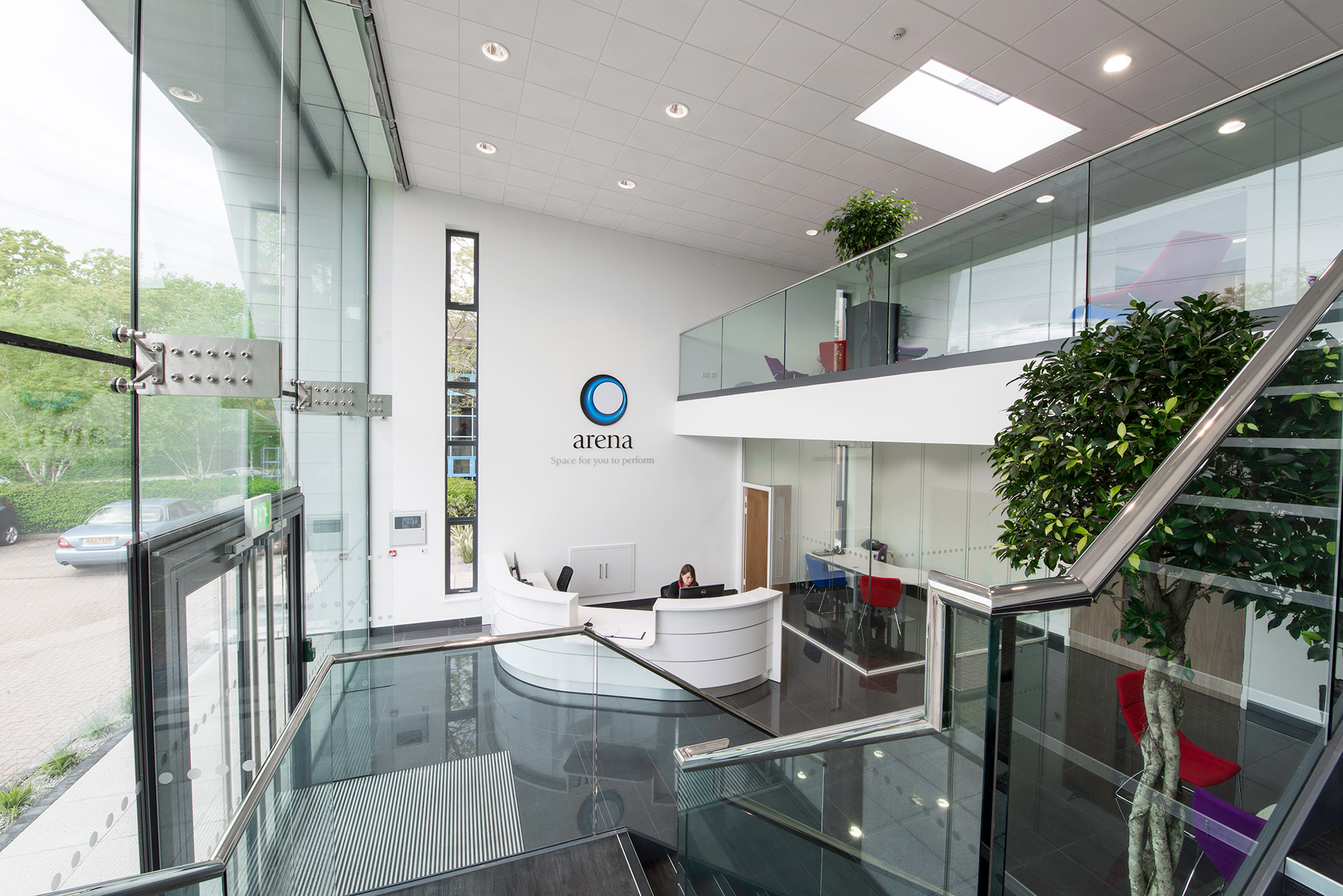 double height interior reception area with dog legged staircase and glass balustrade