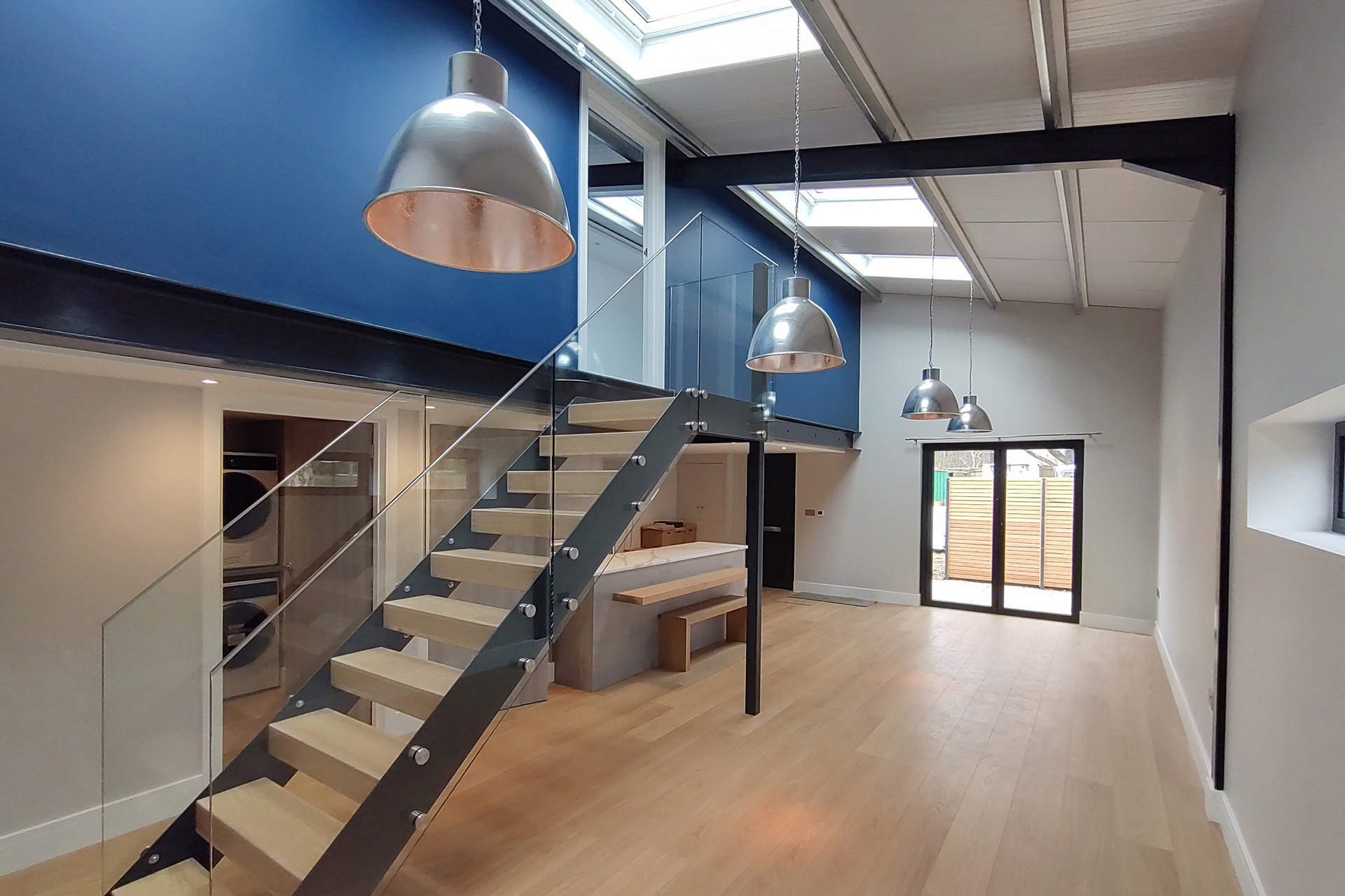 open tread staircase with glass balustrade leading to second floor with blue feature wall