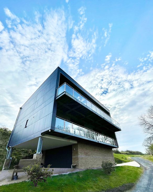 entrance approach view of house with overlapping balcony and garage on first floor