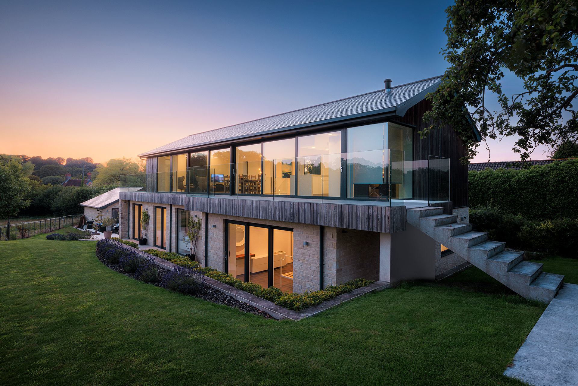 approach view of contemporary house at dusk with lights on