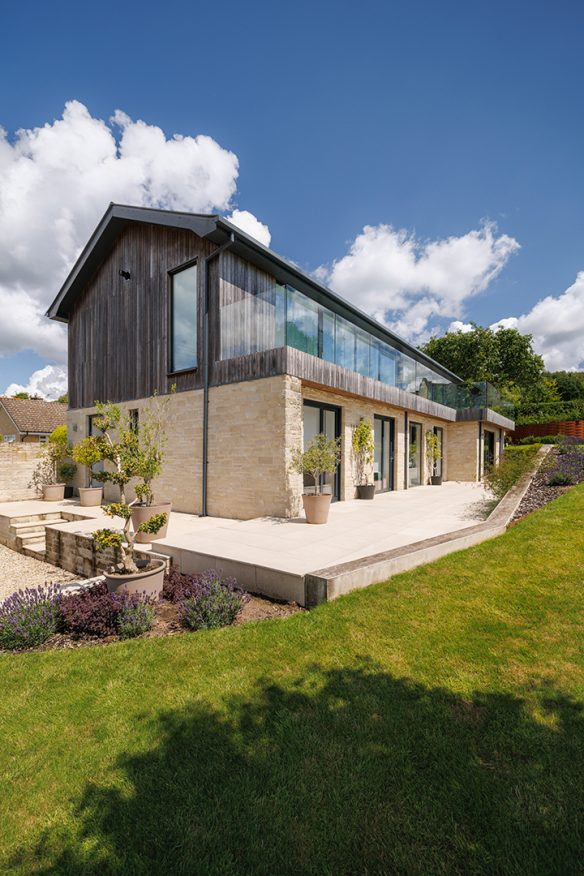 exterior corner of house with stone walls on first floor and timber cladding on second