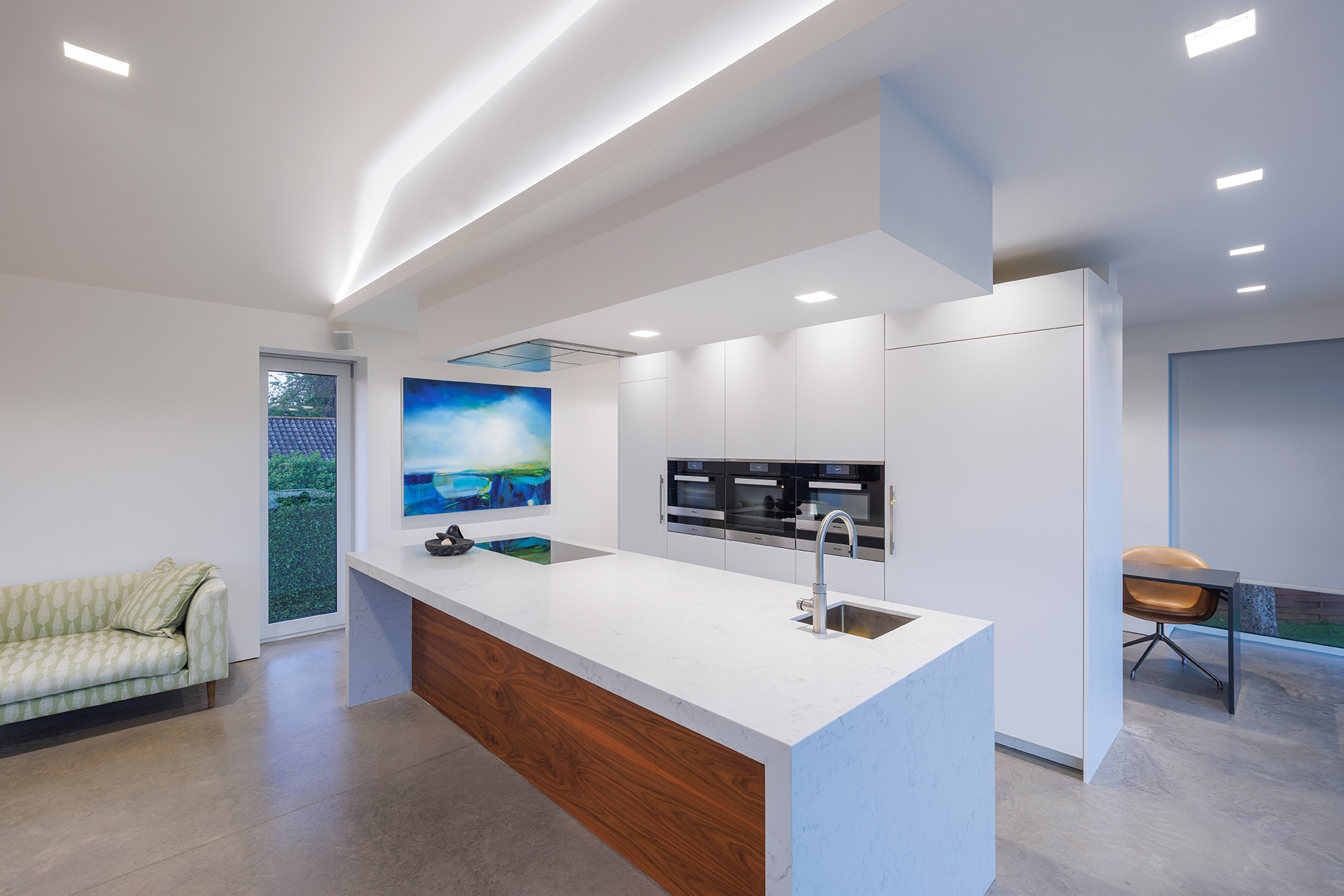 modern kitchen in white tones with cove lights in ceiling