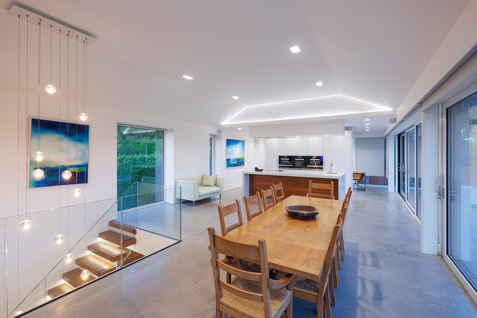 open-plan modern kitchen dining area with wooden table and chairs and staircase leading downstairs