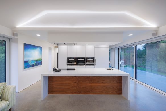 white modern kitchen with cove lighting and large kitchen worktop island
