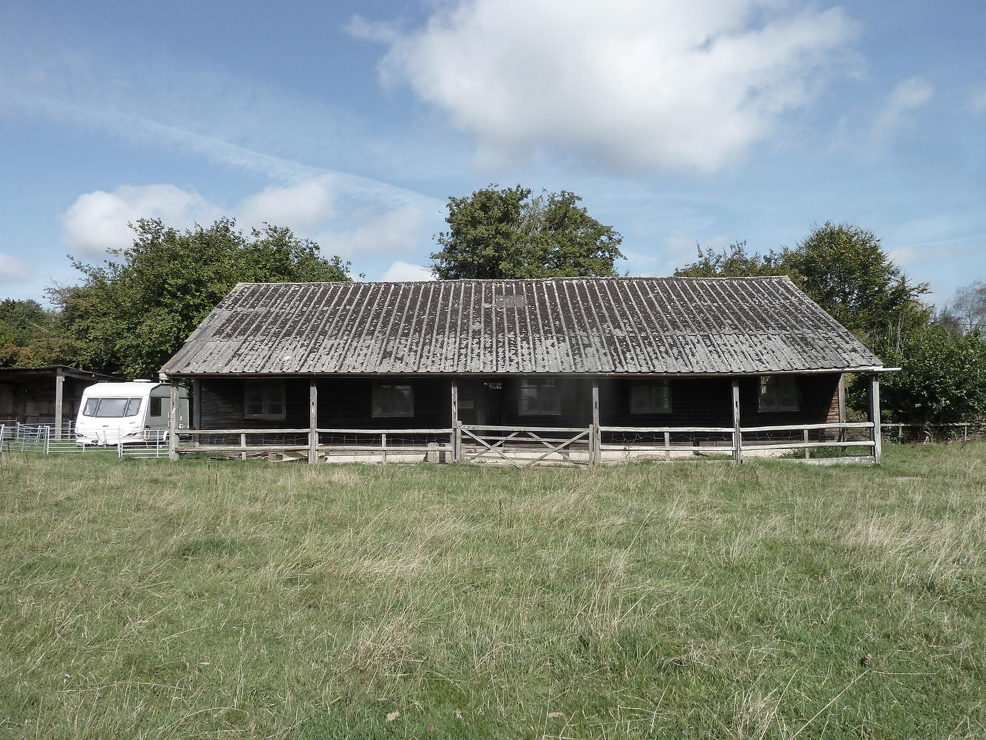 before photo of barn from front with corrugated roof and grass outside