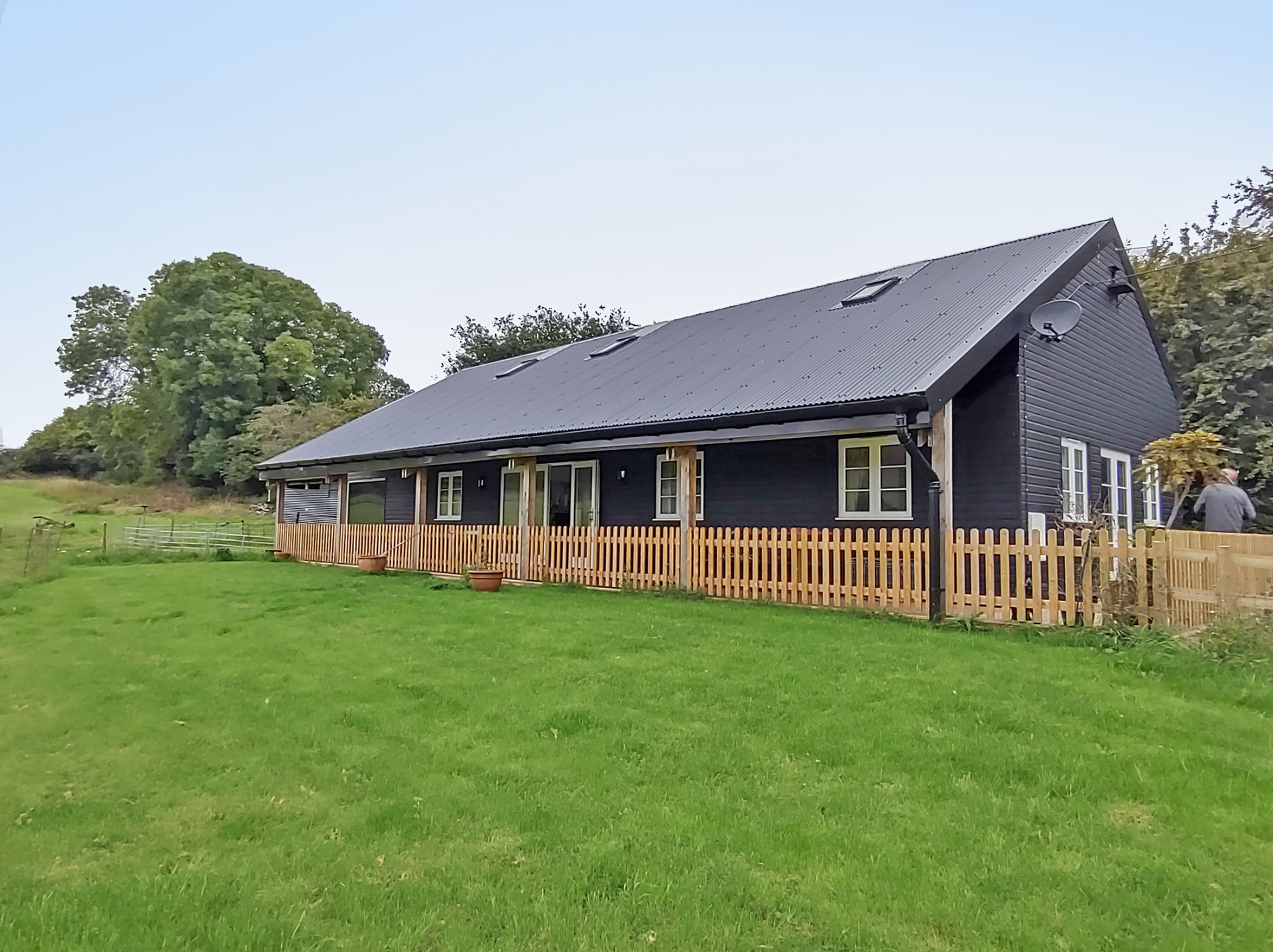 finished converted black barn with wooden fence around veranda