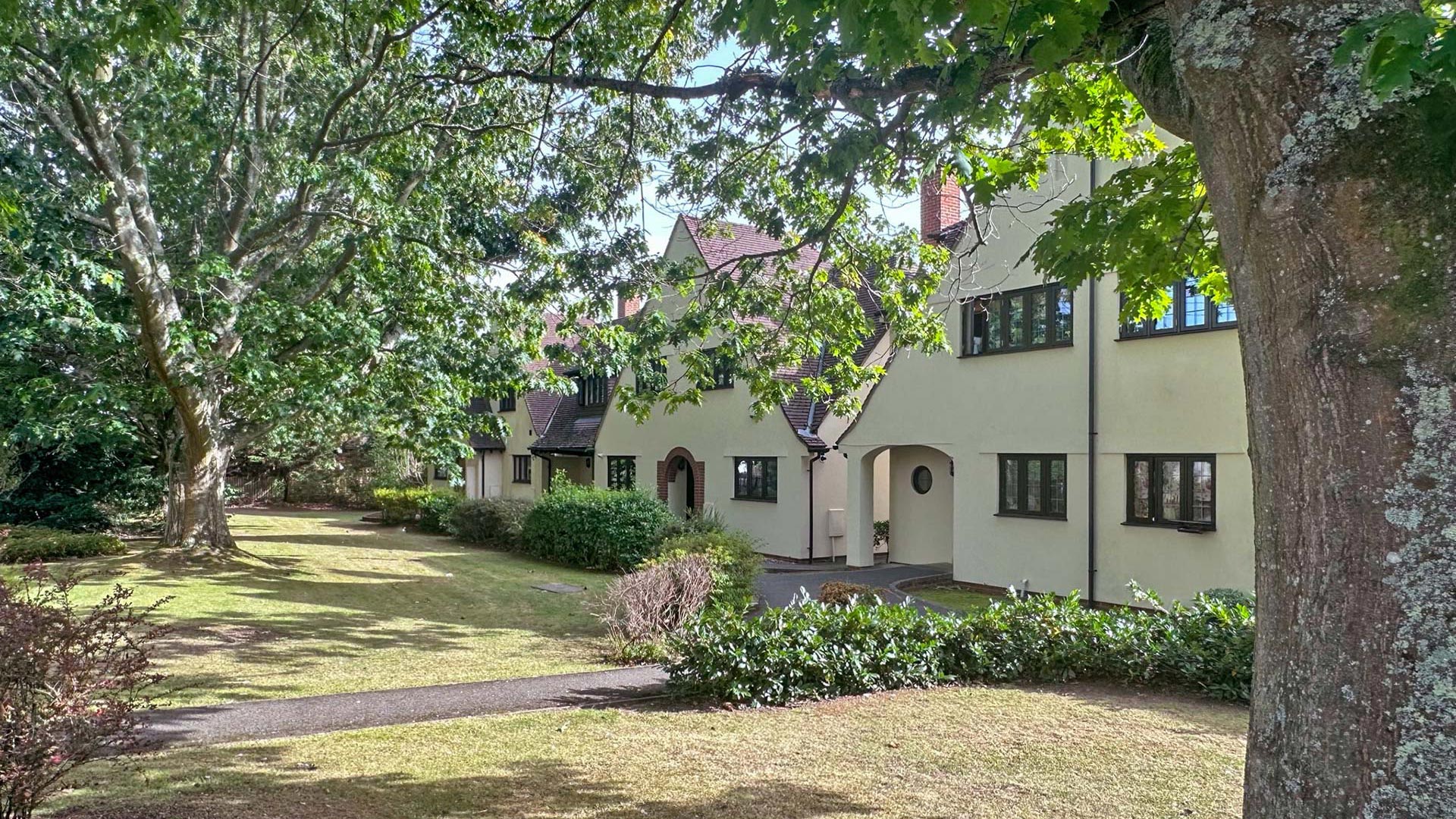 front view of housing from behind trees in garden