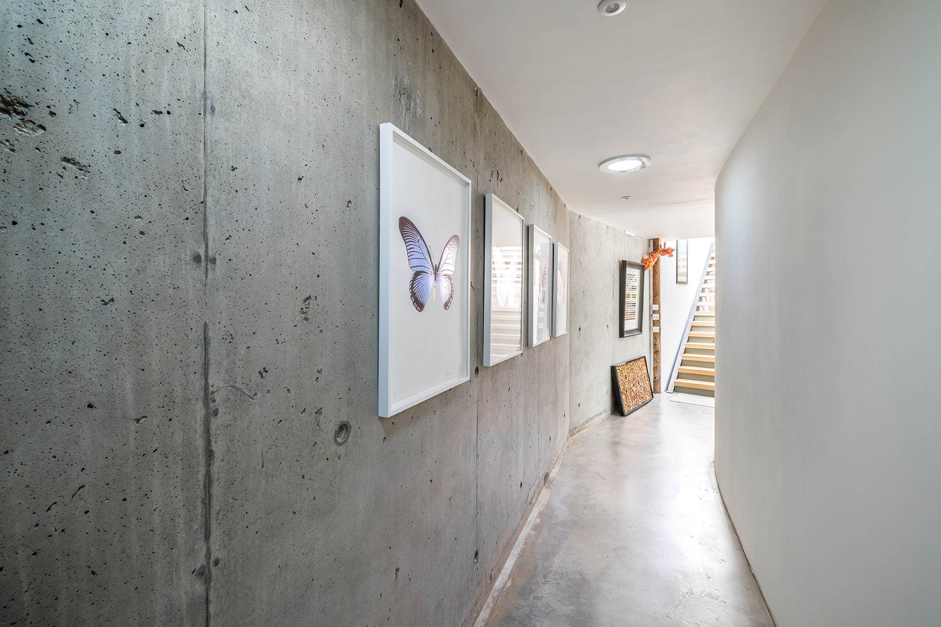 internal corridor in house with modern concrete walls and spotlights with staircase at end