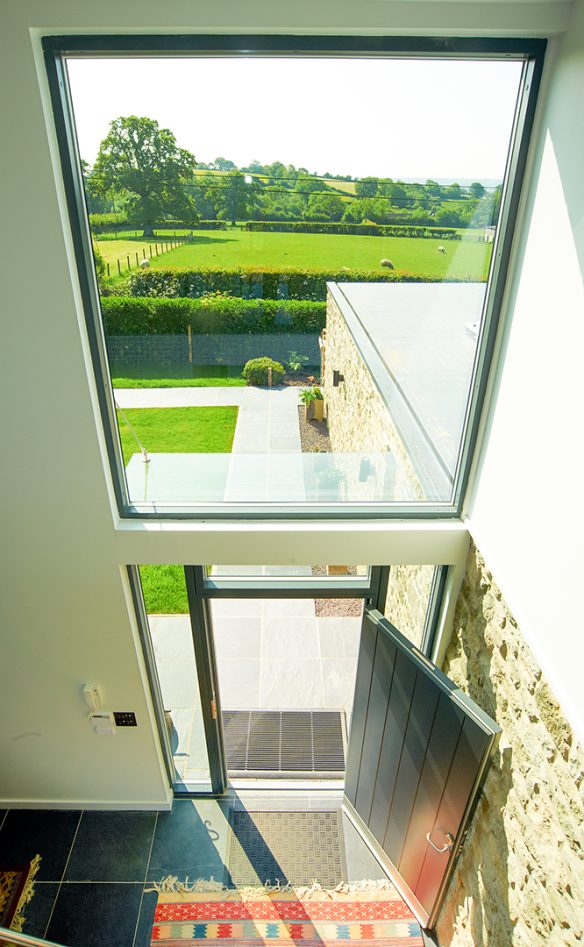 mezzanine view of entrance area to house with double height window overlooking countryside