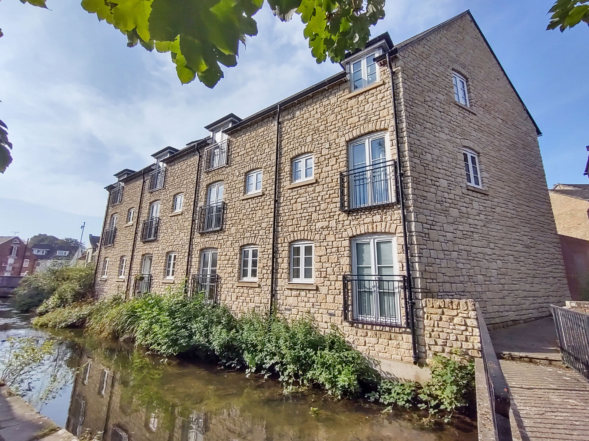 view of flats with stone wall from across river