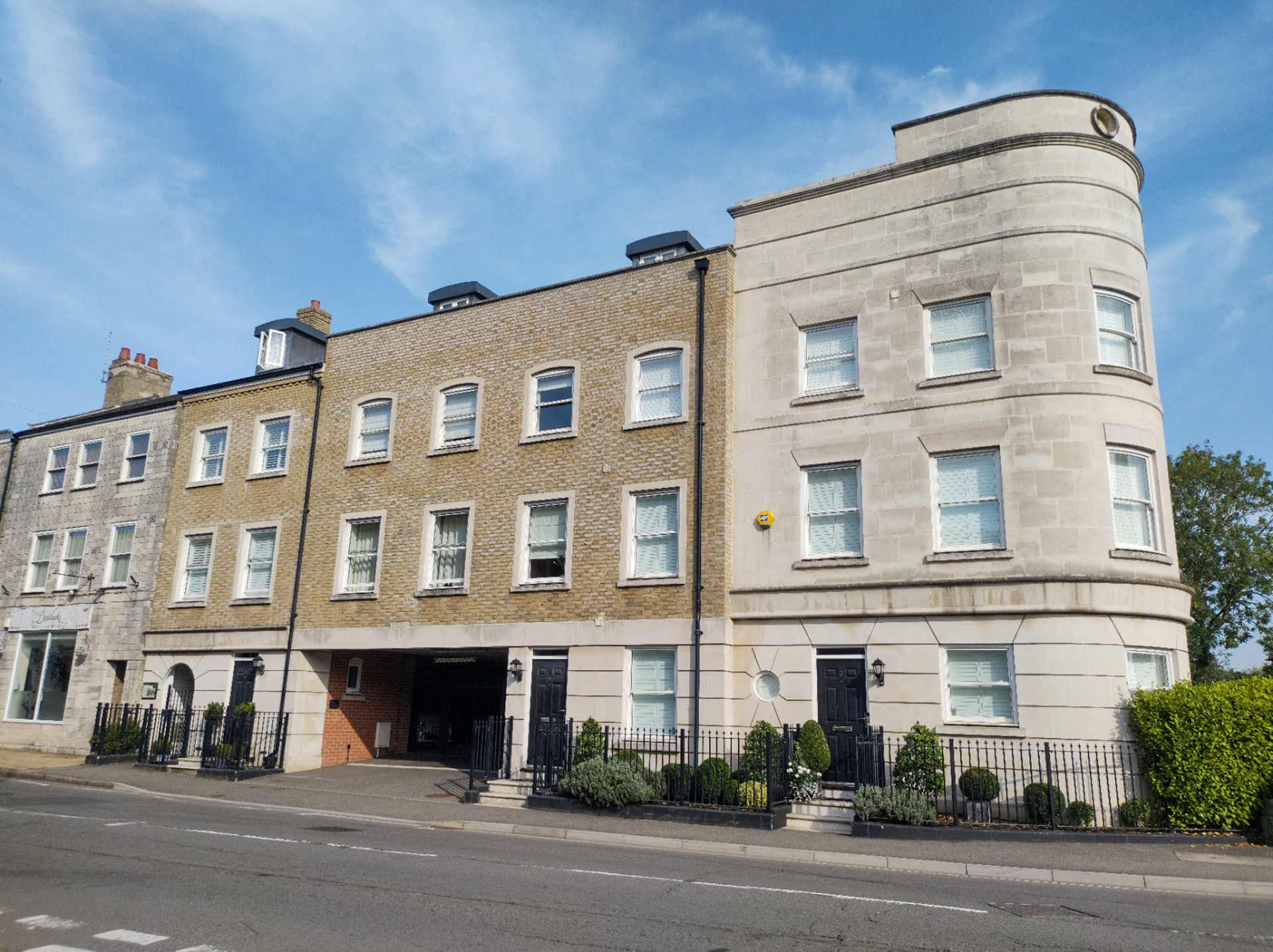 roadside view of flats with featured curved stone wall