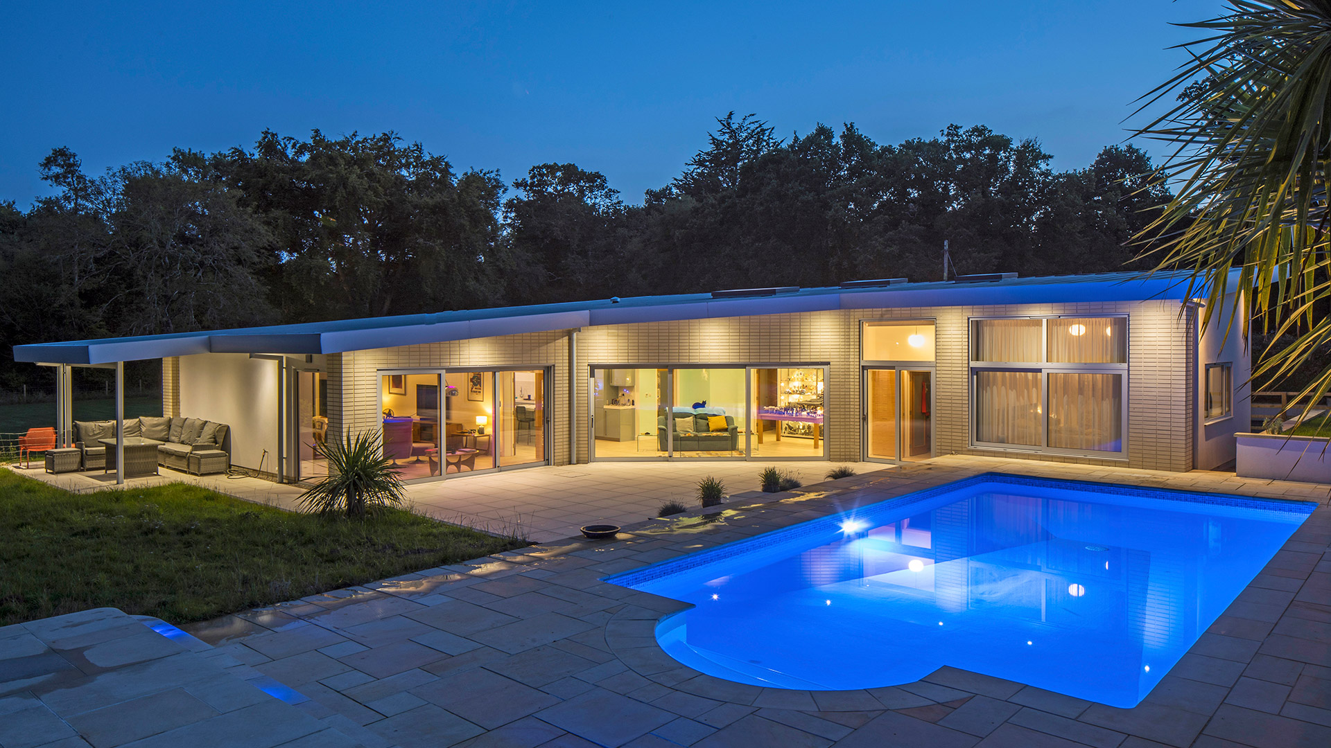 mid century Californian house with outdoor pool and night with lights on