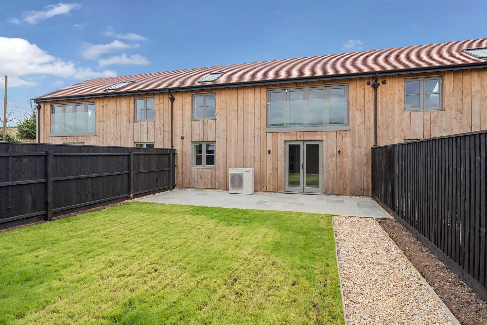 rear view of barn conversion and juliette balcony from garden with air source heat pump