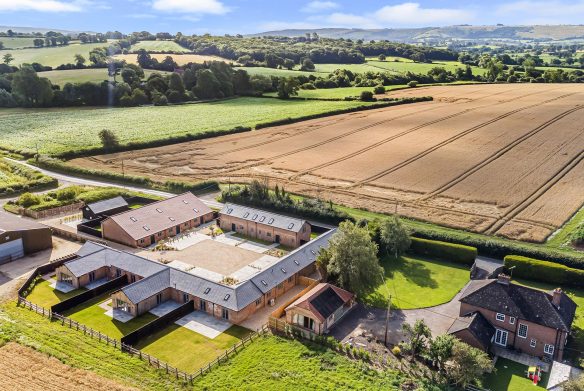 aerial view of farmhouse with courtyard and outbuildings surrounded by countryside