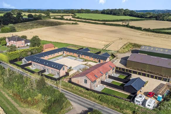 aerial view of farmhouse with courtyard and outbuildings surrounded by countryside